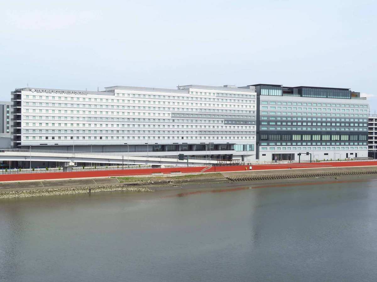 Gebäude des Komplexes Haneda Airport Garden mit "HOTEL VILLA FONTAINE"-Dachbeschriftung, Außenansicht vom Wasser aus