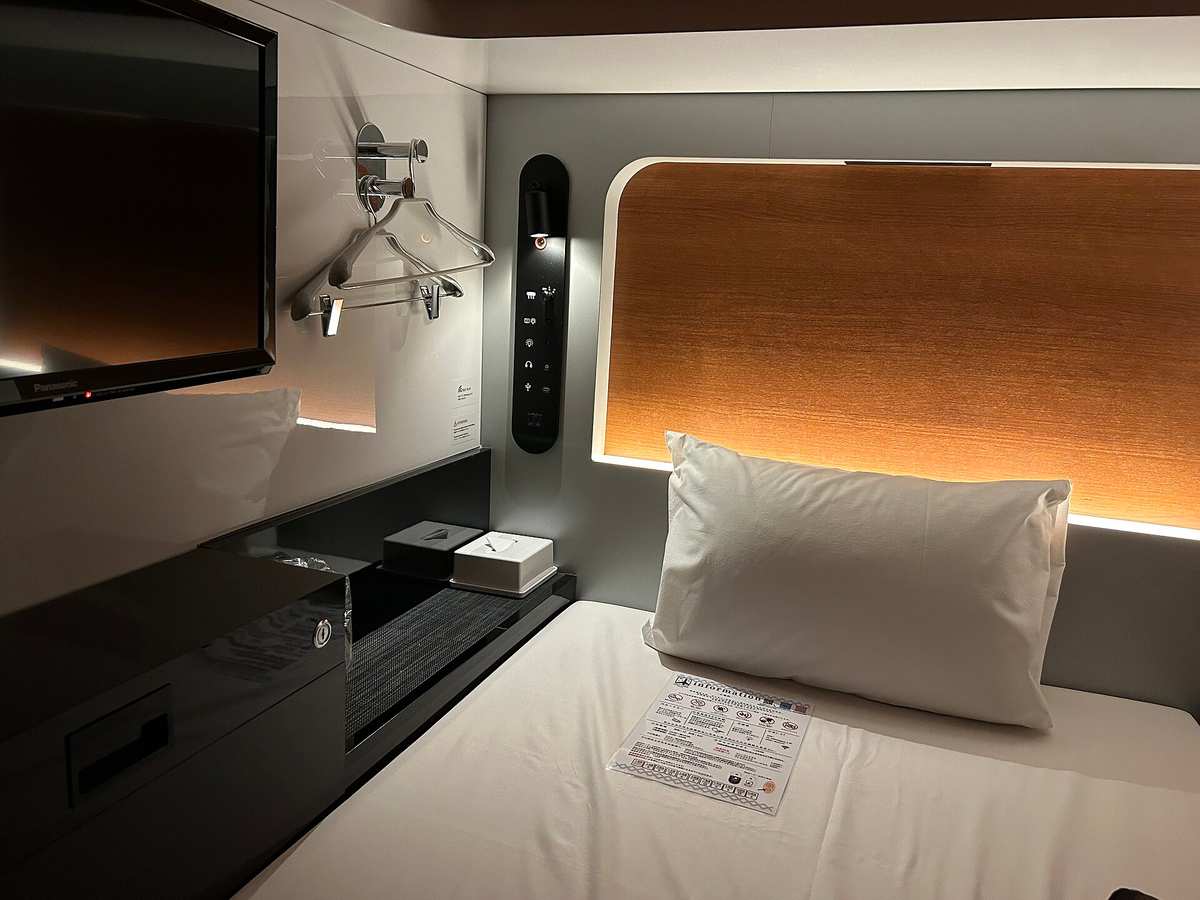 Kapsel im First-Cabin-Kapselhotel mit TV, Steuerpaneel und gepolstertem Bett