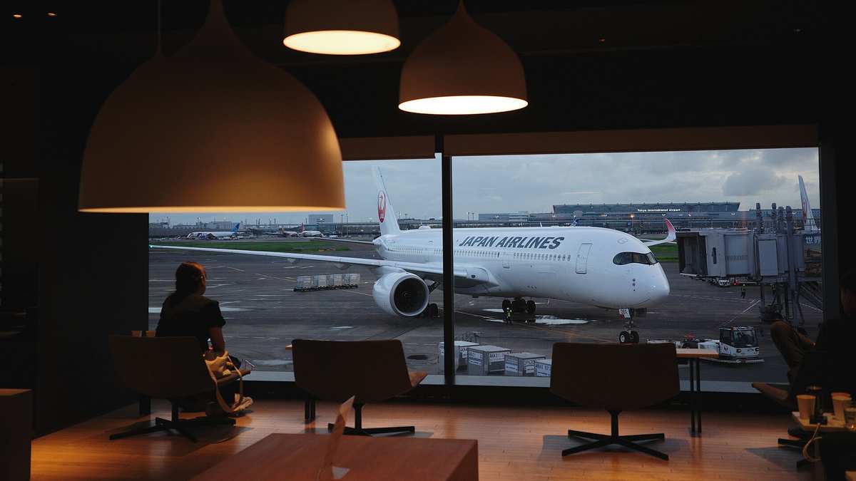 Blick aus einer Flughafen-Lounge in Haneda auf ein Flugzeug am Gate in der Abenddämmerung